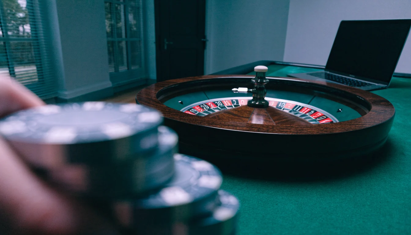 Roulettehjul på grönt bord med casinofärger och stängd laptop